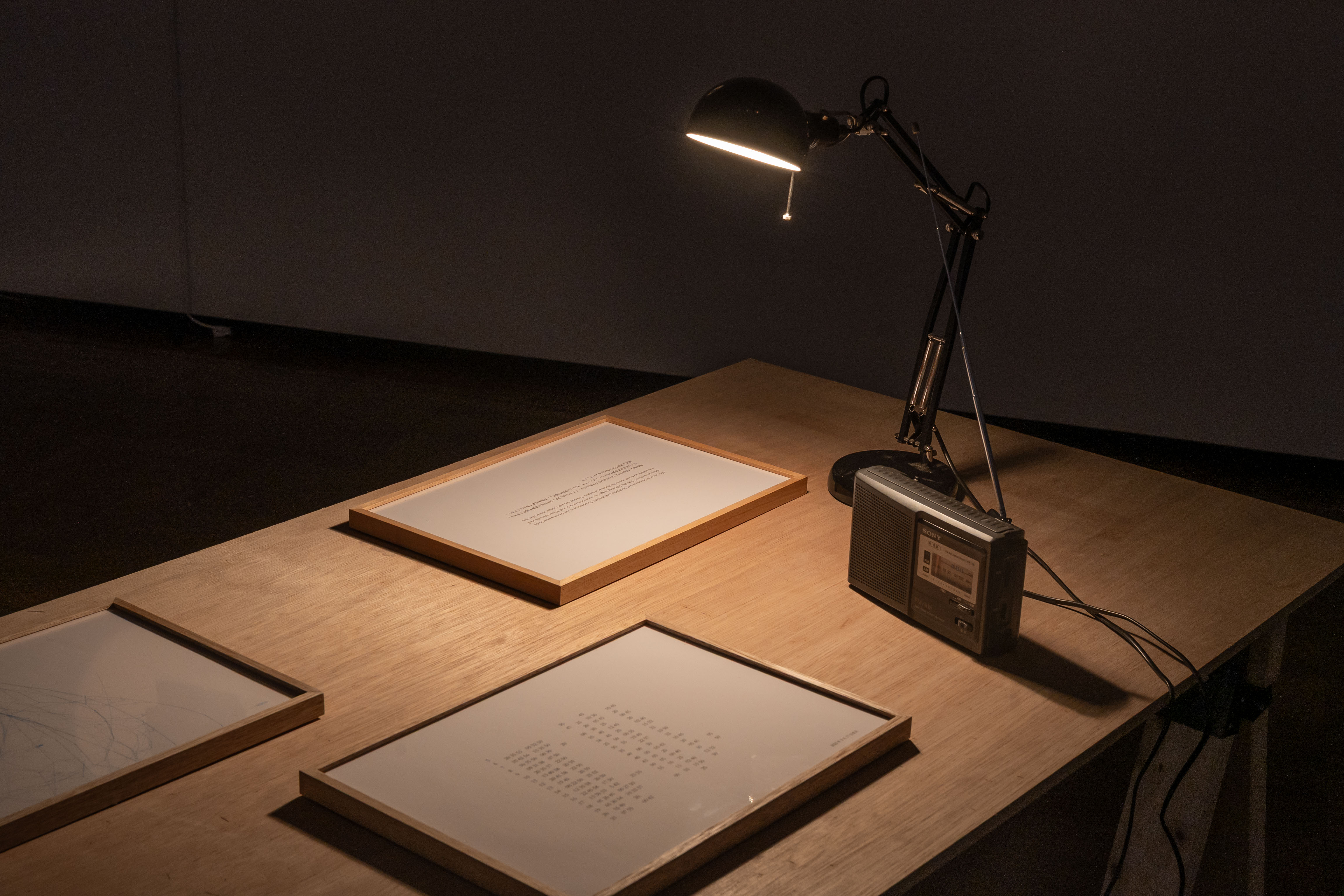 木の作業台の上に置かれたデスクライト、額、古いラジオ